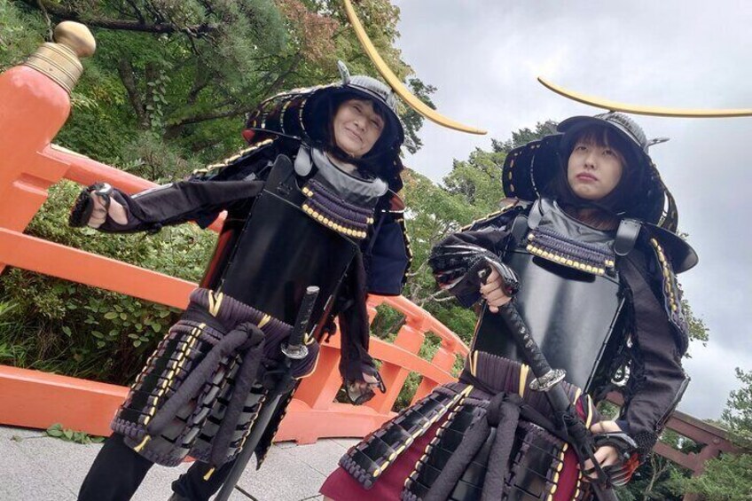 Two individuals in traditional samurai armor standing on a bridge. 2