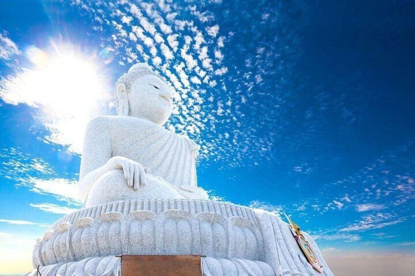 A large white statue of a seated figure against a blue sky with clouds. 1