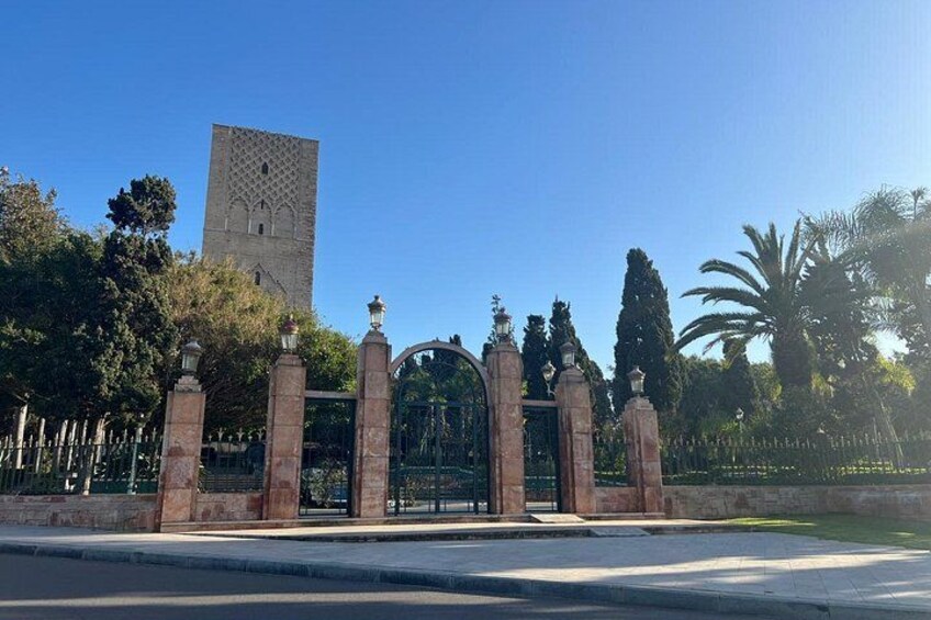 A gated entrance with a decorative archway, a tall tower, and a clear blue sky. 5