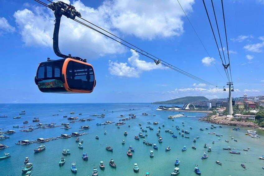 A cable car over a coastal area with numerous boats and a bridge in the background. 2