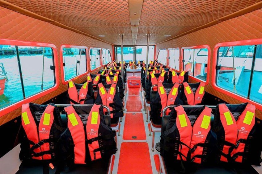 Interior de un barco con filas de asientos, cada uno con un chaleco salvavidas. 2