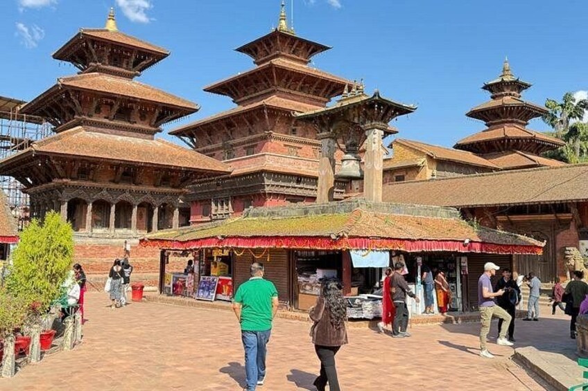 A traditional multi-tiered temple with people walking around. 1