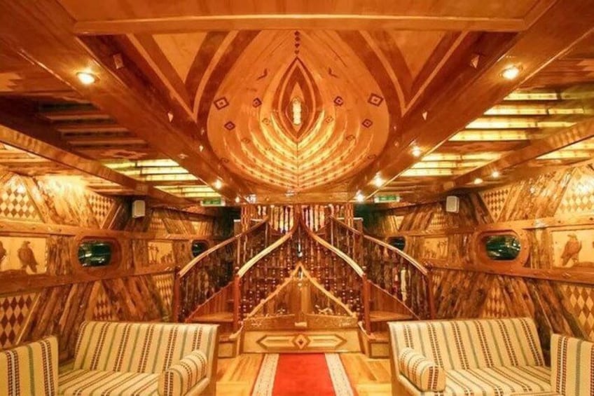 A luxurious interior with a central staircase, ornate wooden walls, and patterned upholstery. 5