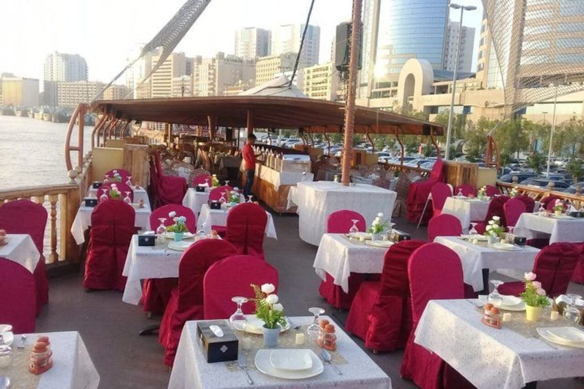 An outdoor dining area with tables set for a meal, overlooking a body of water and a city skyline. 3