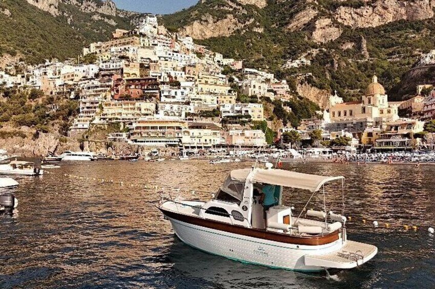 A boat on calm water with a coastal town in the background. 1