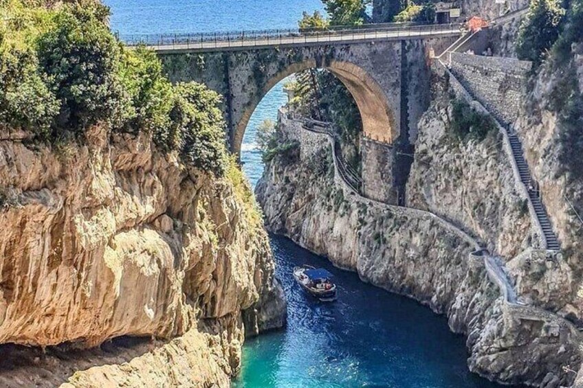 A stone bridge over a river, surrounded by rocky cliffs and a boat. 4