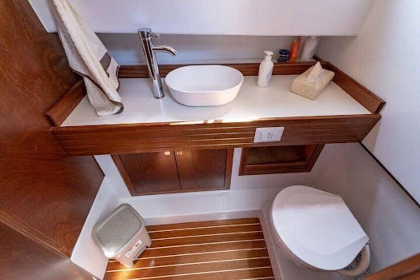 A compact bathroom with a wooden vanity, a white sink, and a toilet. 5