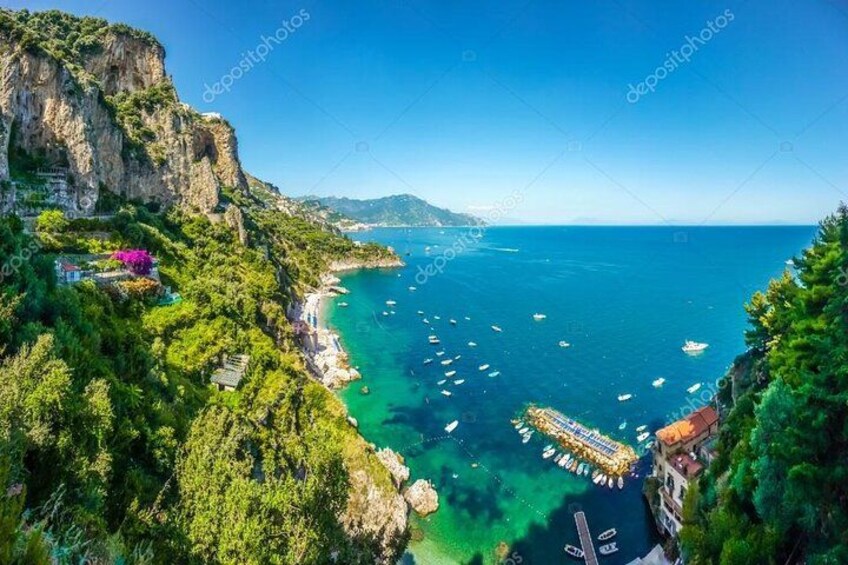A coastal landscape with cliffs, a pier, and boats. 2