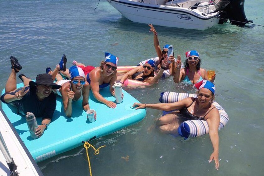 Un grupo de personas en un bote flotando en el agua, con trajes de baño y gorros de natación. 5
