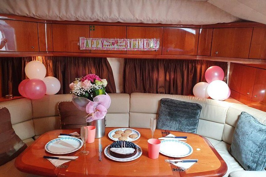 A dining area with a table set for two, a bouquet of flowers, and balloons. 3