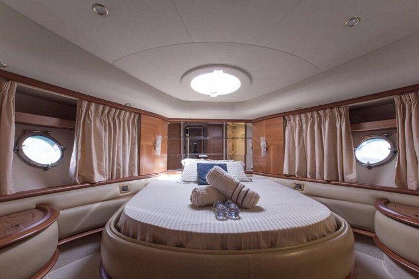 A luxurious cabin with a round bed, wooden paneling, and two windows. 2