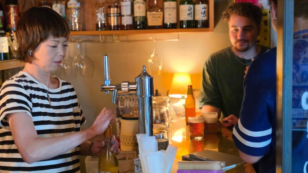 En barista laver en drik ved en bar med et udvalg af flasker i baggrunden. 4