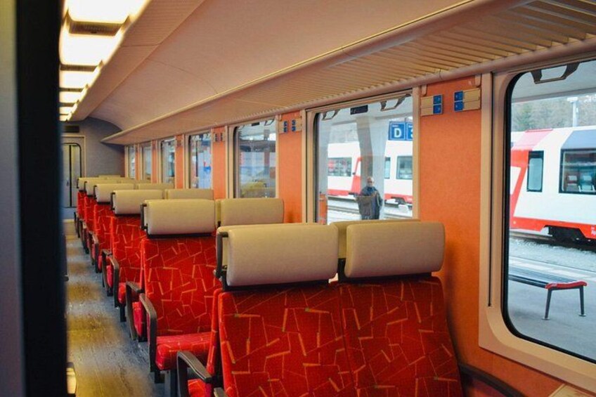 A train interior with red seats and windows. 3