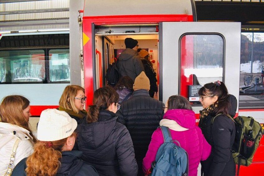 A group of people boarding a red bus with a person climbing the steps. 5