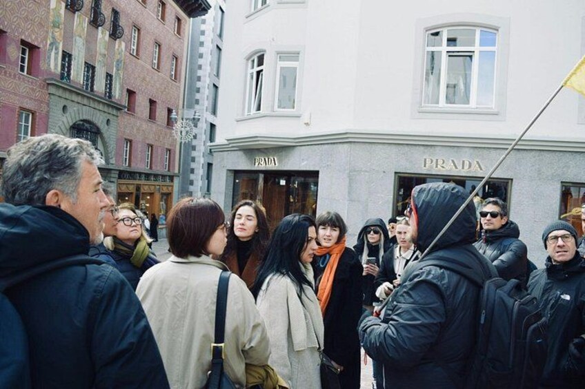 A crowd of people standing in front of a building with the sign 'PRADA'. 2