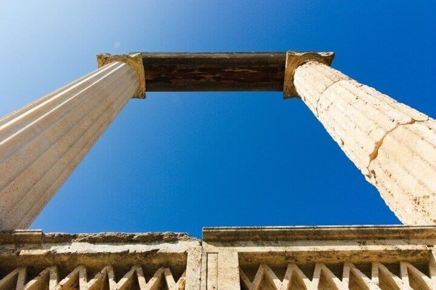 A weathered stone structure with two columns against a clear blue sky. 2