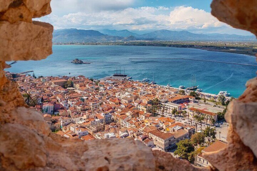 A coastal cityscape with a view of the sea, buildings, and mountains in the distance. 3