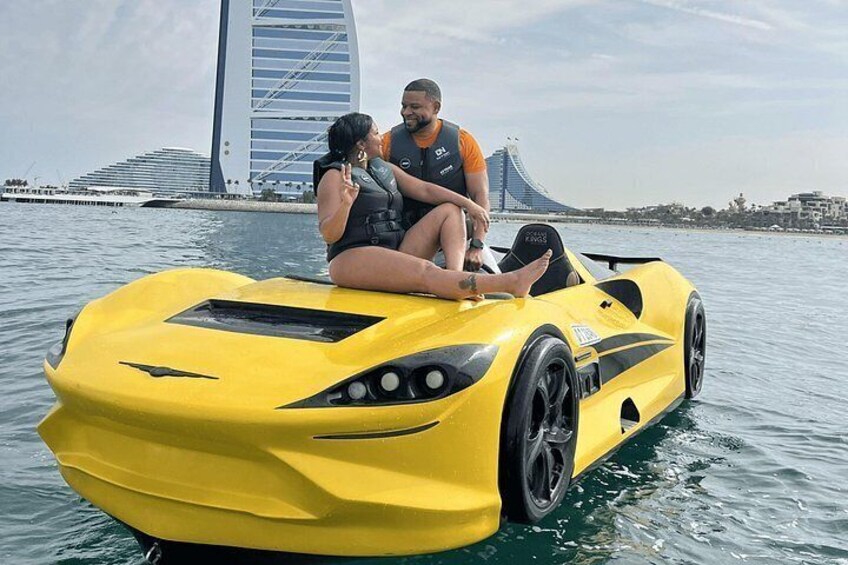 A yellow sports car on water with a bridge in the background. 5