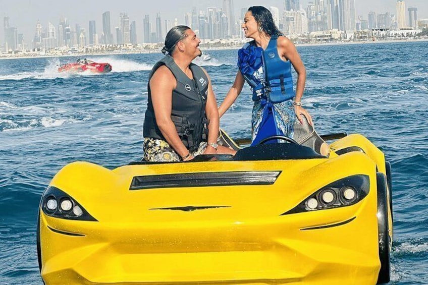 Un bateau à moteur jaune avec deux personnes à bord, une vue sur les gratte-ciel de la ville en arrière-plan et un bateau rouge sur l’eau. 1