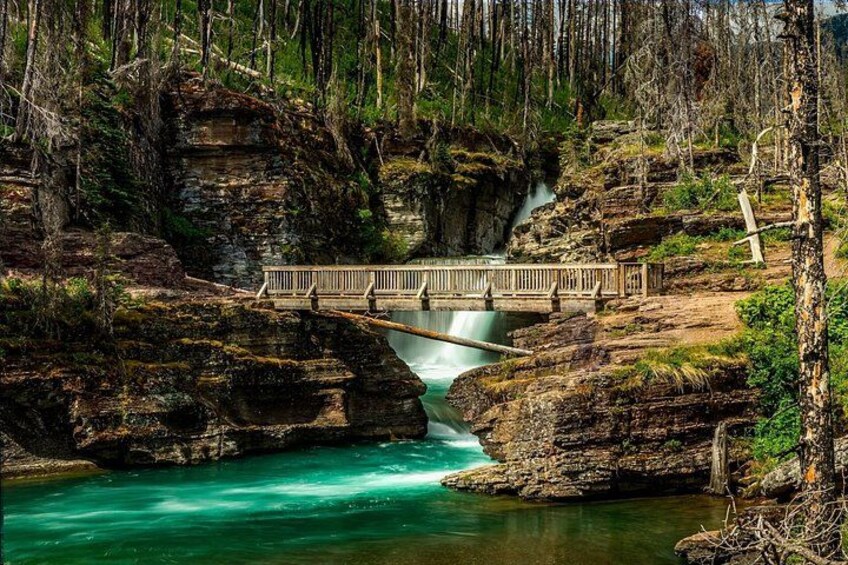 Une rivière turquoise serpentant à travers un défilé rocheux, un pont de bois et une forêt dense. 3