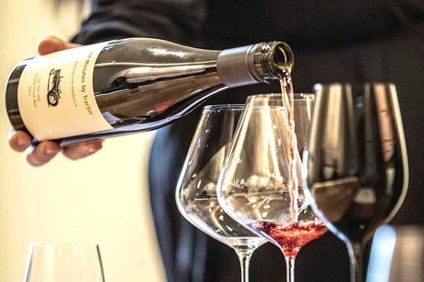 En person hælder vin fra en flaske i et glas. 3
