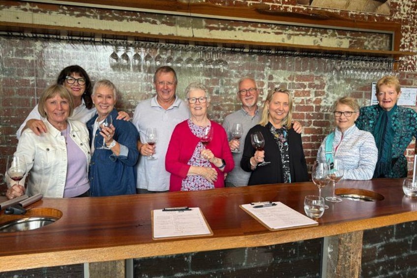 Un grupo de personas de pie junto a una barra de madera con copas de vino. 4