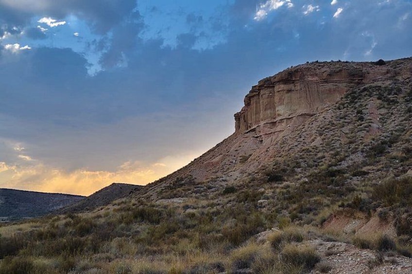 A desert landscape with a prominent rock formation and sparse vegetation. 4