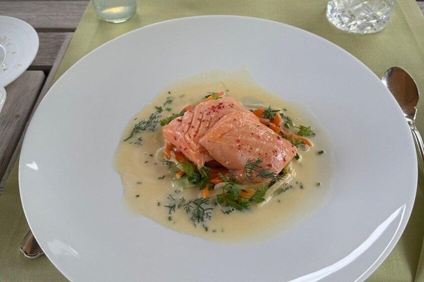 A plate of food with salmon, vegetables, and a creamy sauce. 5