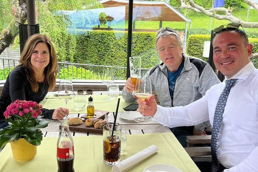 Three people at an outdoor table with drinks, a bottle of Coca-Cola, and a glass of wine. 2