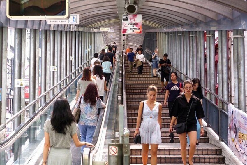 A pedestrian bridge with people walking and standing, metal railings, and a sign for Candine Express. 4