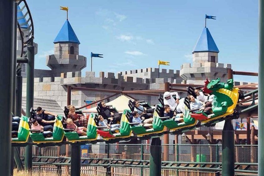 A dragon boat ride with riders in green and yellow boats, a castle-like structure in the background, and a clear sky. 2