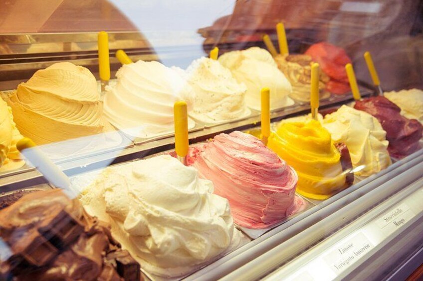 A variety of ice cream flavors in a display case with yellow handles. 5