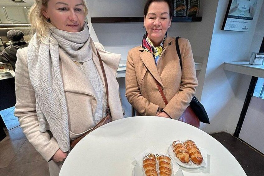 Two people standing at a table with pastries. 4