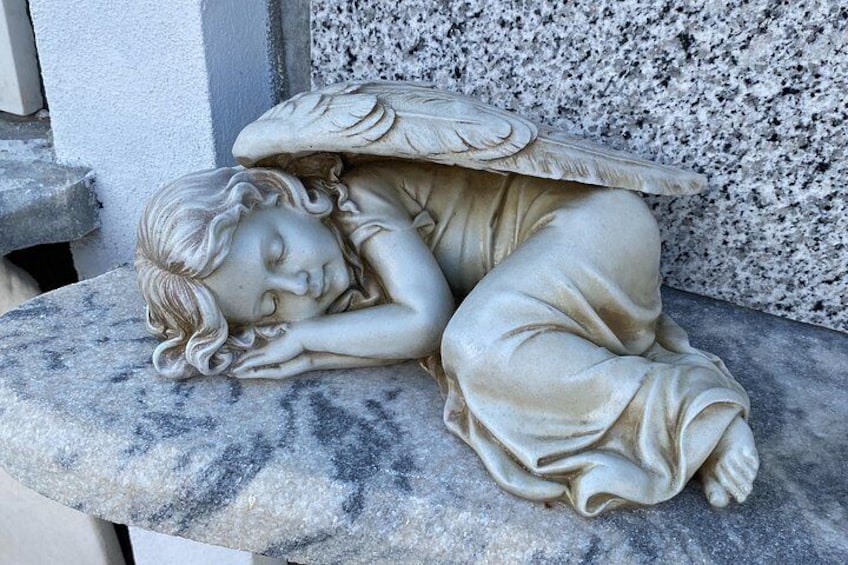 A stone bench with a sculpture of a sleeping angel. 5