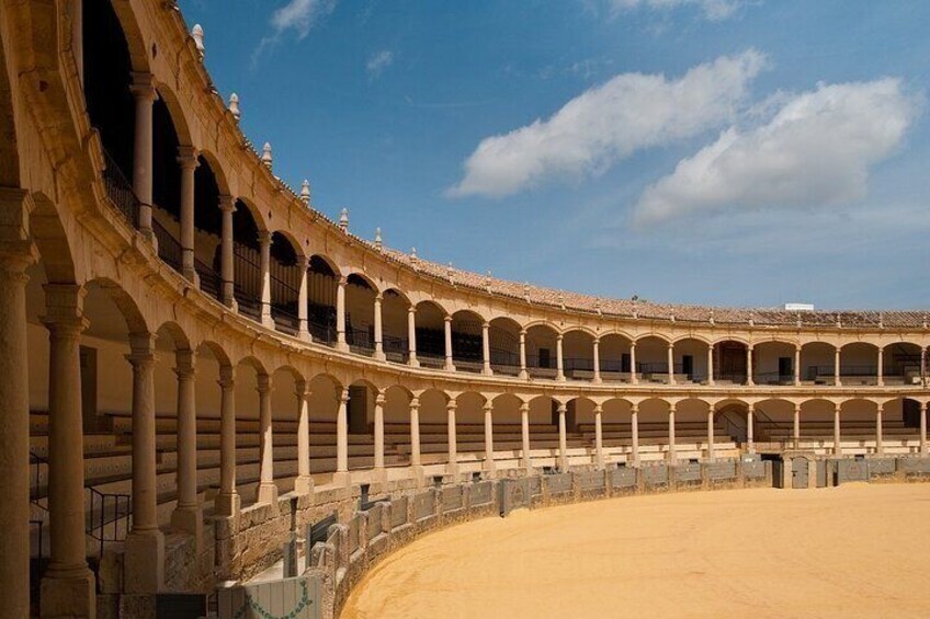 Un gran anfiteatro al aire libre con múltiples niveles de arcos y suelo de arena. 4