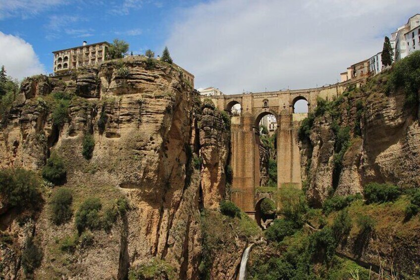 Un puente histórico con arcos, un edificio en un acantilado y un río abajo. 1
