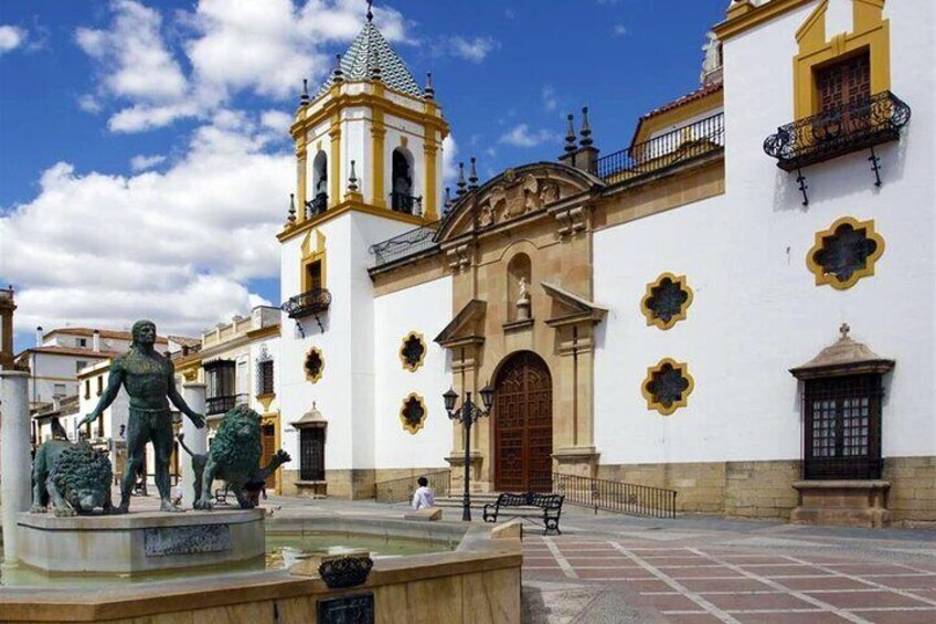 Una plaza con una fuente, una estatua y un edificio con un campanario. 5