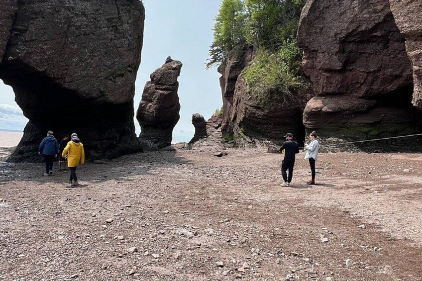 A rocky landscape with large boulders and people walking. 4