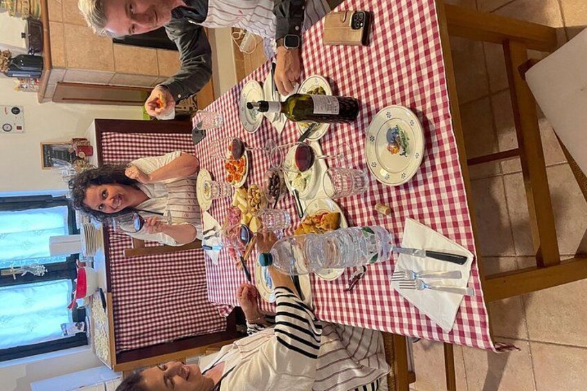 A dining table with a checkered tablecloth, plates, glasses, and bottles. 5