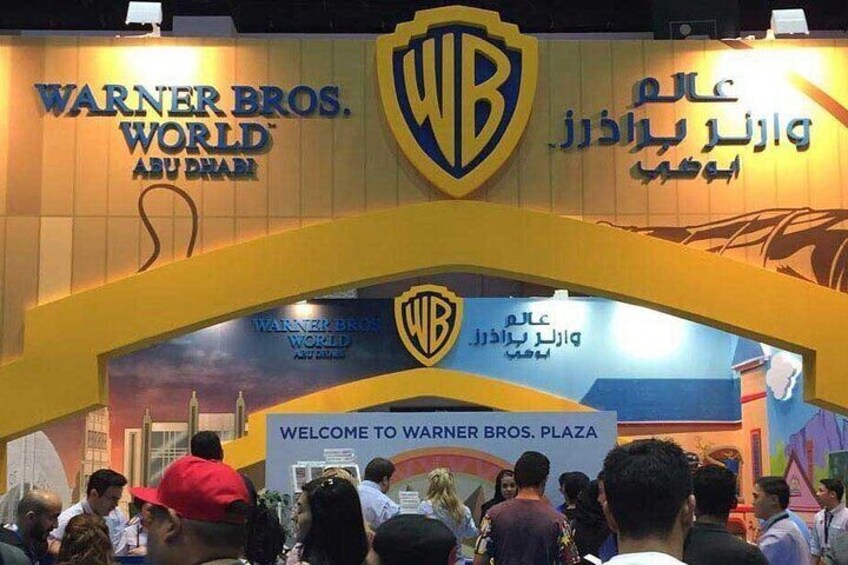 Warner Bros. Plaza entrance with WB logo, Arabic text, and a crowd of people. 5