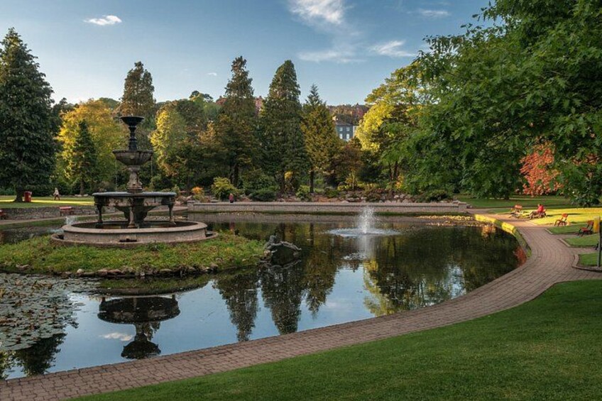 A serene park with a central fountain, a pond, and surrounding trees. 2