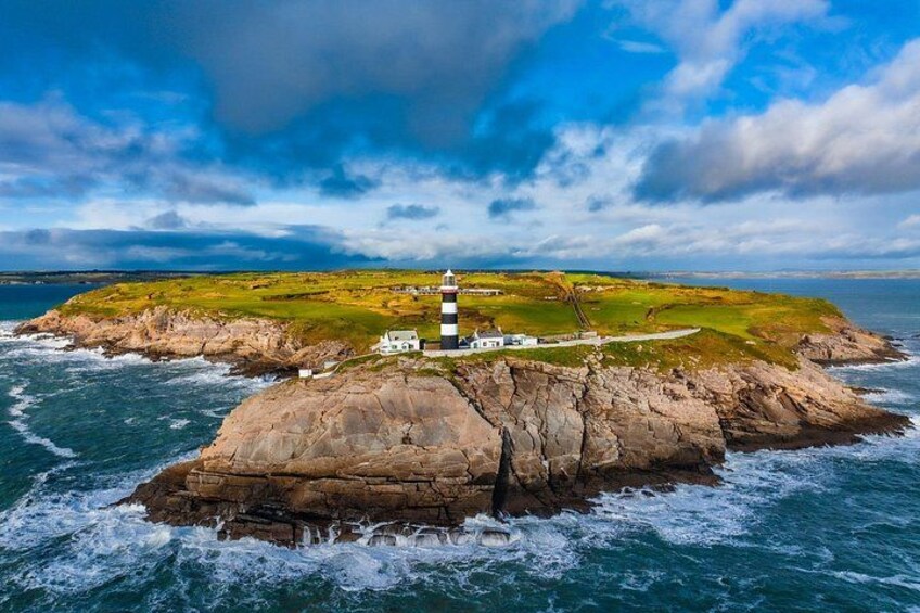 A lighthouse on a rocky island with a grassy landscape and a clear sky. 5