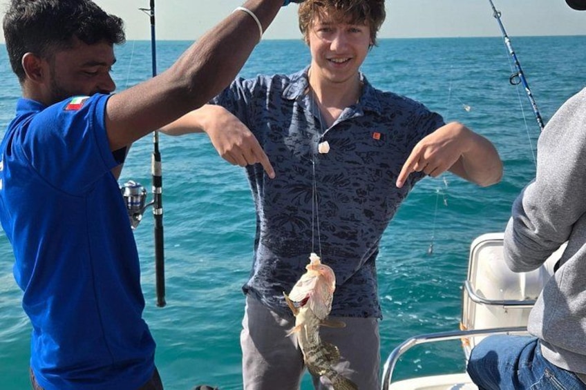 Two people on a boat holding a fish. 2