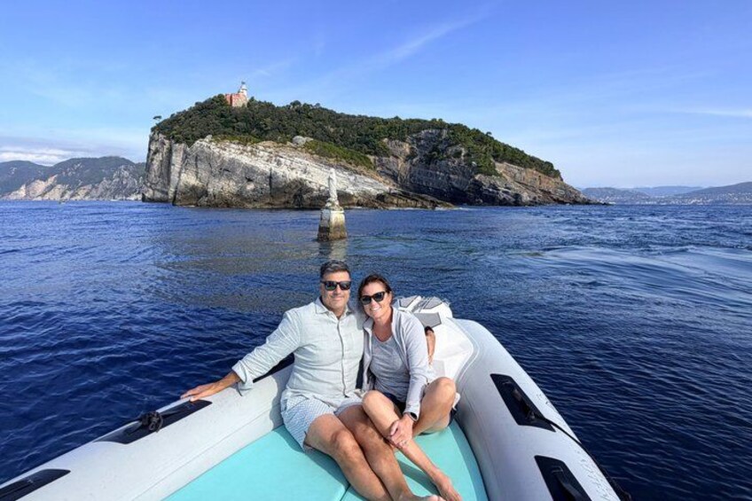 Dos personas en un bote, con una isla rocosa y un faro al fondo. 5