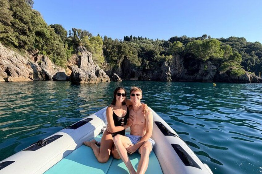 Dos personas en un bote en un cuerpo de agua, con acantilados rocosos y vegetación al fondo. 3