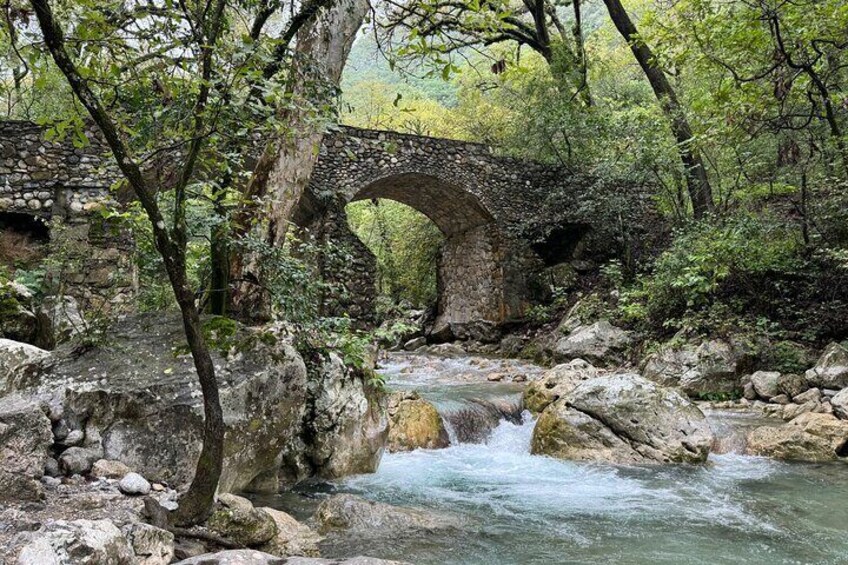 Un pont de pierre enjambant une rivière aux eaux vives, entouré d’une végétation luxuriante. 2