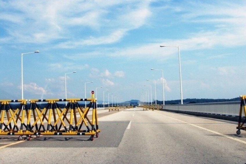 Un puente con barreras amarillas, farolas y cielo despejado. 3