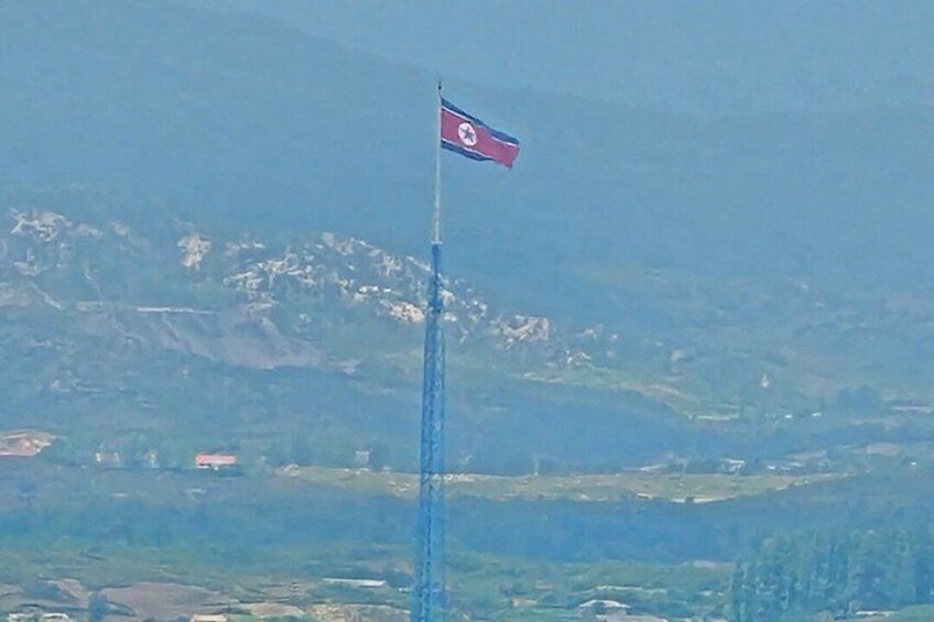 Eine Flagge auf einem Fahnenmast vor einer bergigen Landschaft. 2