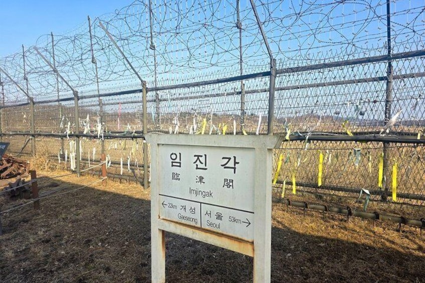 Un cartel con indicaciones hacia Imjingak y un área cercada con alambre de púas. 5