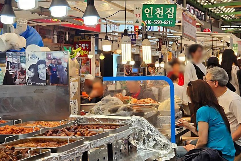 A food market with various food stalls, people eating, and a sign with a phone number. 2